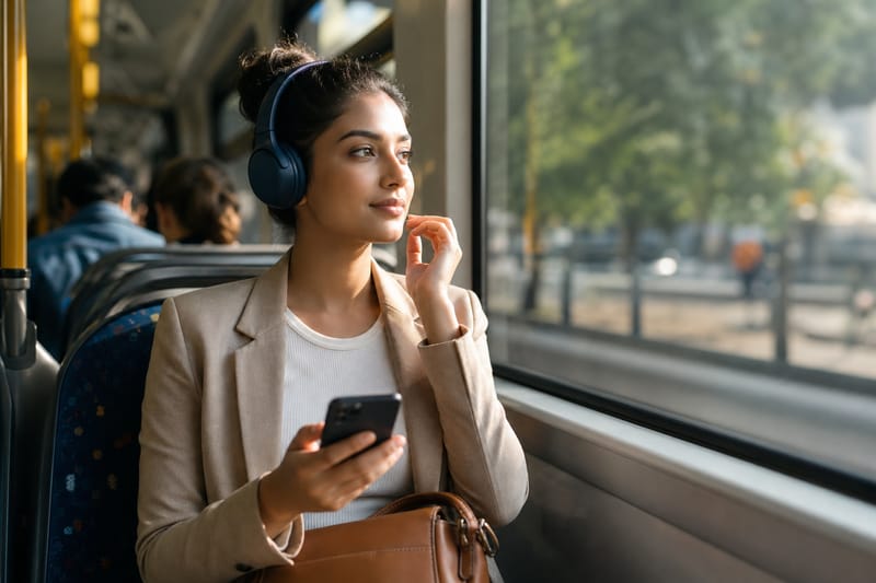 Une personne avec un casque audio parlant à voix basse dans un train bondé, vue à travers une fenêtre avec les lumières de la ville qui défilent.