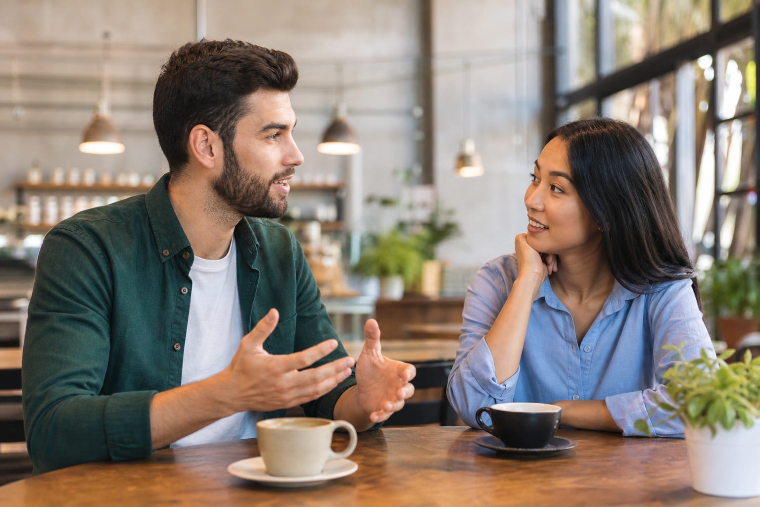 Dues persones xerrant amb un cafè, una inclinada endavant amb expressió d'interès mentre la conversa continua.